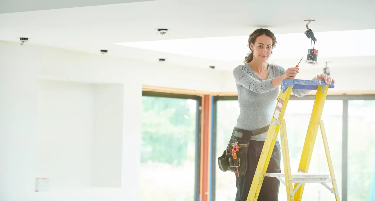Female technician fixing ceiling lamp